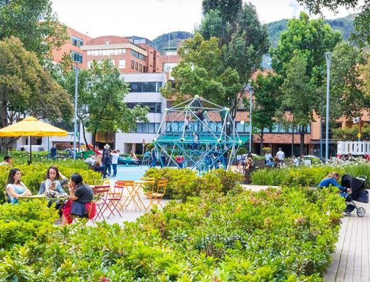 Plano general: “Parque de la 93 en Bogotá, zona urbana para caminar y descansar”. Bancas/personas: “Viajeros descansando en el Parque de la 93, Bogotá”. Noche/luces: Ambiente nocturno alrededor del Parque de la 93 en Bogotá”.