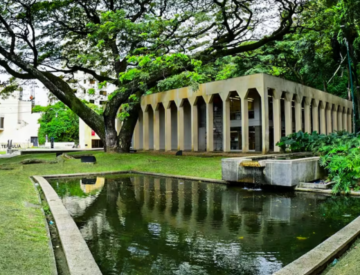 Edificio del Museo La Tertulia en Cali con arcadas blancas, plazoleta de entrada y esculturas modernas bajo palmeras tropicales