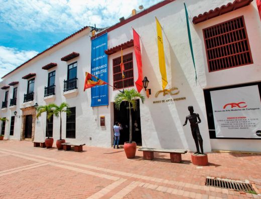 Fachada del Museo de Arte Moderno de Cartagena en la Plaza de San Pedro Claver, con edificio blanco colonial y baluarte de San Ignacio al fondo
