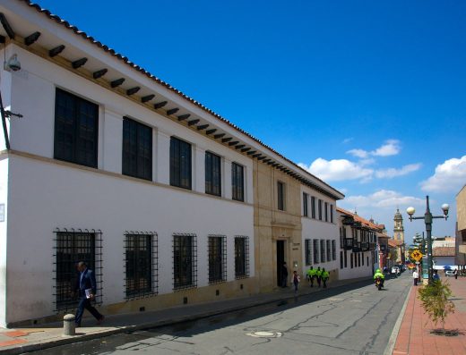 Patio colonial del Museo Botero en Bogotá con arcos blancos, columnas de madera oscura y vegetación tropical en La Candelaria
