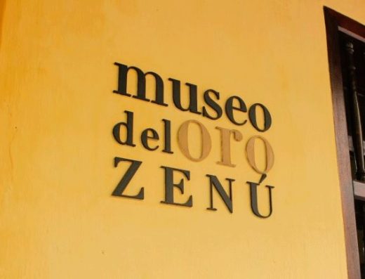 Piezas de oro zenú en vitrina del Museo del Oro Zenú Cartagena: pectoral jaguar, orejeras granuladas y cerámica ritual en iluminación dramática.