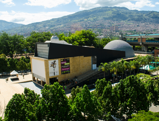 Planetario de Medellín con domo plateado futurista integrado al Parque de los Deseos, arquitectura moderna y visitantes en plazoleta exterior