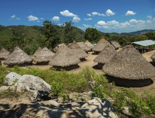 Vista de la Sierra Nevada de Santa Marta con picos nevados al fondo y laderas cubiertas de selva verde que descienden hacia la costa del Caribe colombiano.