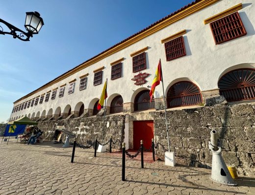 Museo Naval del Caribe Cartagena fachada amarilla con cañones coloniales, estatua naval y bandera colombiana en Calle San Juan de Dios