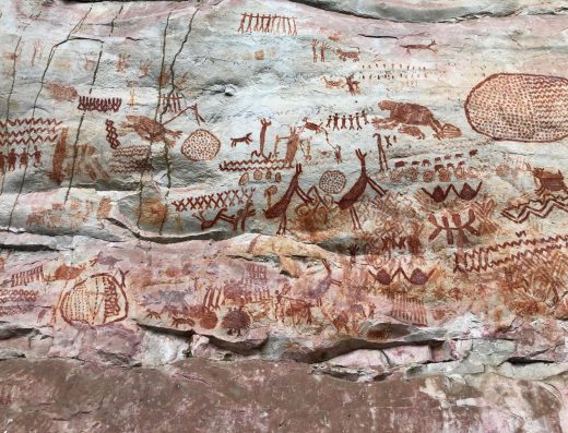 Pinturas rupestres rojas en roca de arenisca de la Serranía de la Lindosa con animales, figuras humanas y patrones