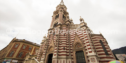 Fachada del Santuario Nuestra Señora del Carmen en Bogotá con franjas alternadas rojo y blanco, arquitectura gótica y campanario en La Candelaria