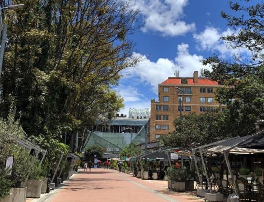 Zona T Bogotá de noche con fachadas iluminadas de Andino, terrazas llenas, multitudes elegantes y palmeras en Zona Rosa.
