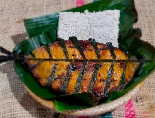 Pescado moqueado cocinado sobre brasas con hojas de plátano en una preparación ancestral indígena