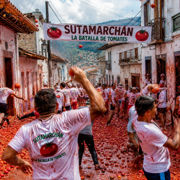 Personas participando en la tradicional batalla de tomates en Sutamarchán, Boyacá, durante un festival cultural y turístico en Colombia.